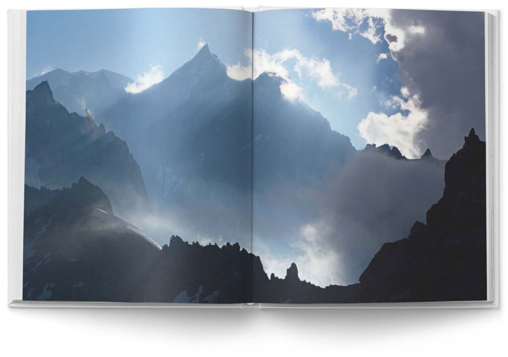 Buchdesign „MOUNTAINS“, National Geographic: Ein stimmungsvolles Bild, das große Berge in mehreren Eben von hinten von der Sonne beleuchtet zeigt. Zwischen den Bergen schlängeln sich Wolken, im Vordergunrd sind Bergzinnen zu sehen.