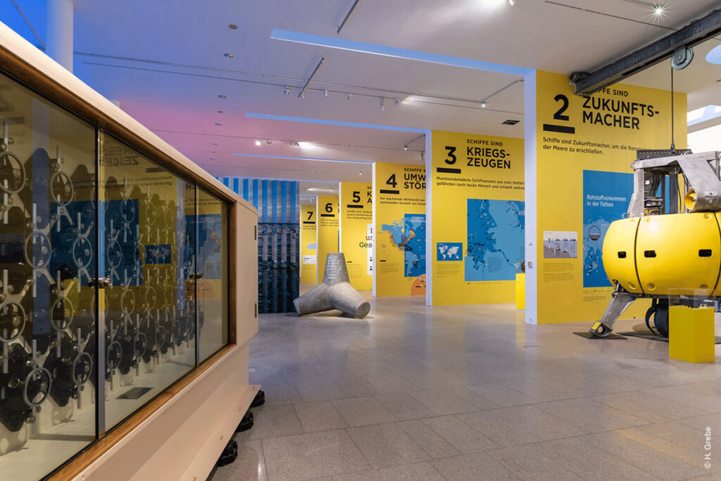 Blick in die Ausstellung „CHANGE NOW“ im Deutschen Schiffahrtsmuseum Bremerhaven. Mehrere Großformatige Wandtafeln mit Infografiken sind zu sehen.